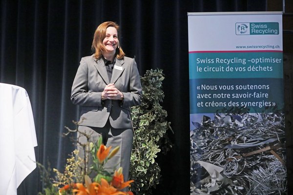 [Translate to Französisch:] Frau steht auf Podium und spricht zu Publikum