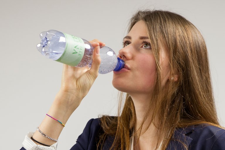 [Translate to Italienisch:] Frau trinkt aus PET-Getränkeflasche.